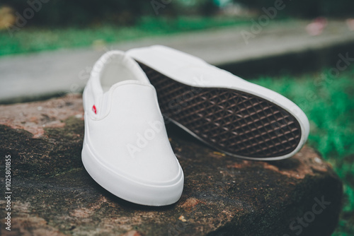 White canvas sneakers slip on men's footwear fashion on stone.