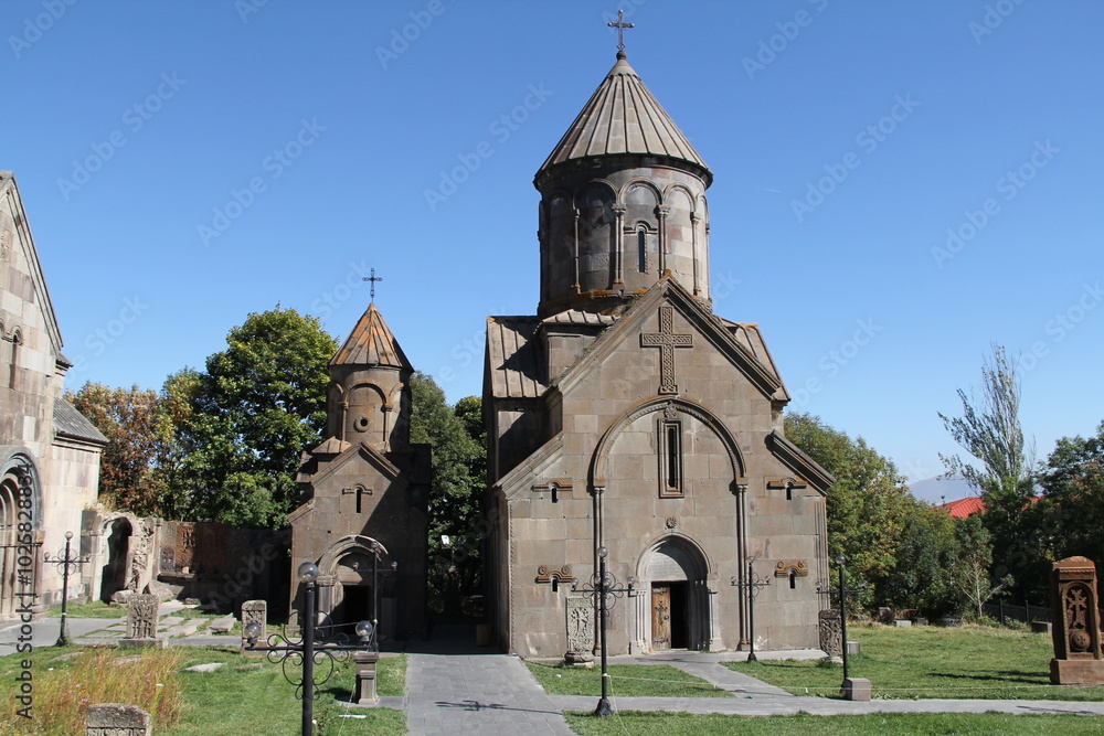 The ancient church stands in a lush green field. Its rough-hewn stone walls and simple cross roof are surrounded by trees and thick, vibrant grass, showcasing its historical significance. The ancient church stands in a lush green field. Its rough-hewn stone walls and simple cross roof are surrounded by trees and thick, vibrant grass, showcasing its historical significance.