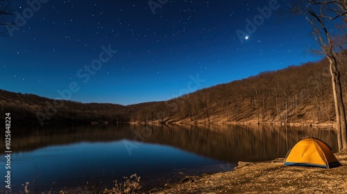 A lone yellow tent sits on the shore of a still lake under a starry sky.