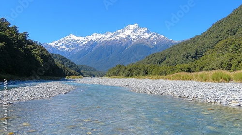 A winding river flows through a valley with snow-capped mountains in the distance