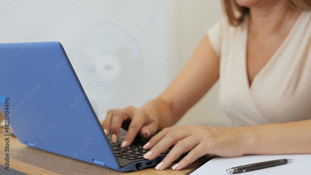 Fototapeta premium Woman working at laptop, focused and productive. Her hands move swiftly over laptop keyboard, showing efficiency. Ideal for themes like remote work, technology, and daily tasks with a laptop.