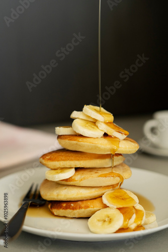 Pancake soffici con sciroppo d'acero su sfondo scuro, colata di sciroppo con banane photo