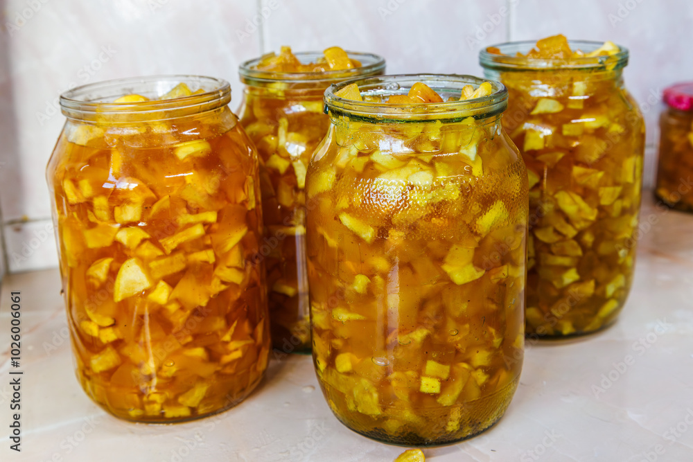 Glass jars with apple jam on kitchen table before closing with lids for preservation. Glass jars with apple jam on kitchen table before closing with lids for preservation.