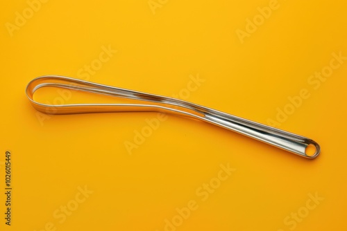 Stainless steel kitchen tool on a bright yellow background