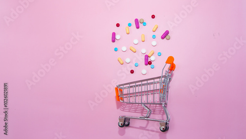 Capsules, pills are scattered out from trolley shopping cart on pink background. Concept for shopping and purchasing. Medical science, medicine, health insurance. Pharmacy, Drugstore.