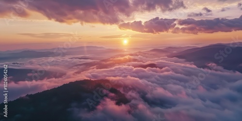 Aerial view of mountain ranges covered in mist at sunrise.