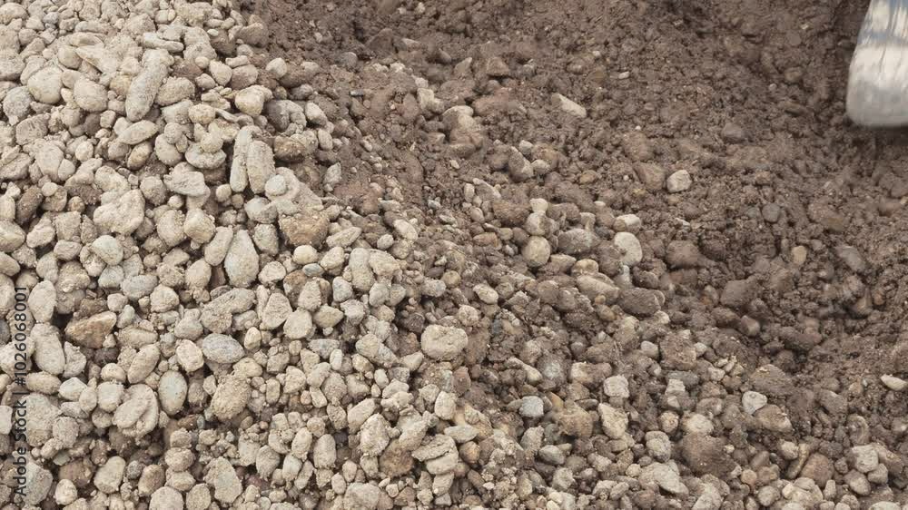 A man, a worker, loads sand and gravel mixtures into a garden wheelbarrow for construction. A man, a worker, loads sand and gravel mixtures into a garden wheelbarrow for construction.