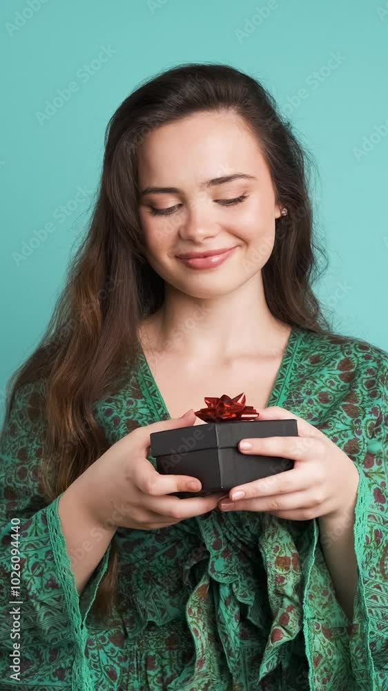 Happy young woman receiving gift box in blue studio Happy young woman receiving gift box in blue studio