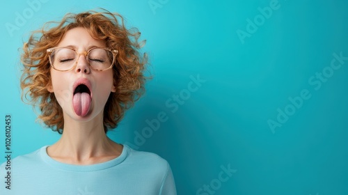 A woman with curly hair and glasses sticks out her tongue, creating a humorous and playful ambiance that conveys emotion and carefree spirit.