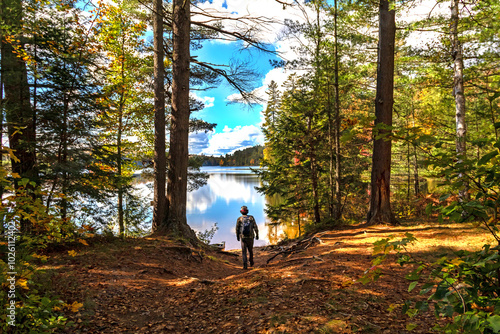 Walking towards Adirondack pond in St Regis Canoe Wilderness Area with peak fall foliage on a peaceful calm morning