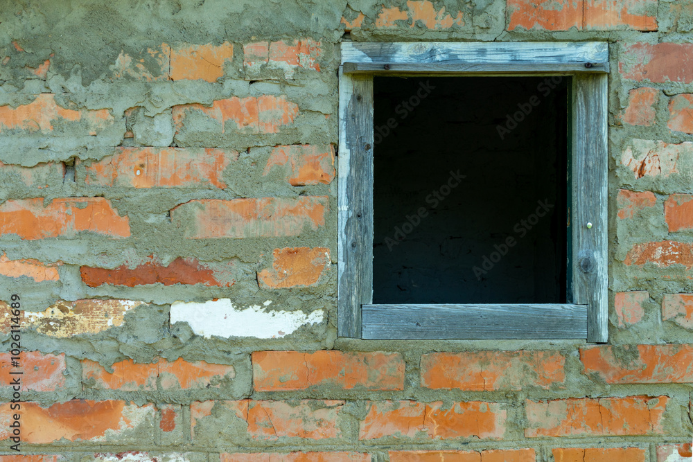 Fototapeta premium A wooden frame in a brick wall of an abandoned house