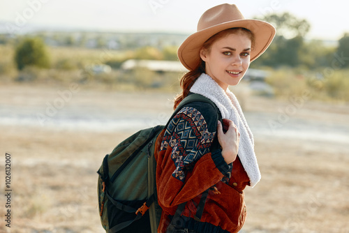 Happy hiker in a sunlit field with backpack and hat, enjoying the great outdoors photo