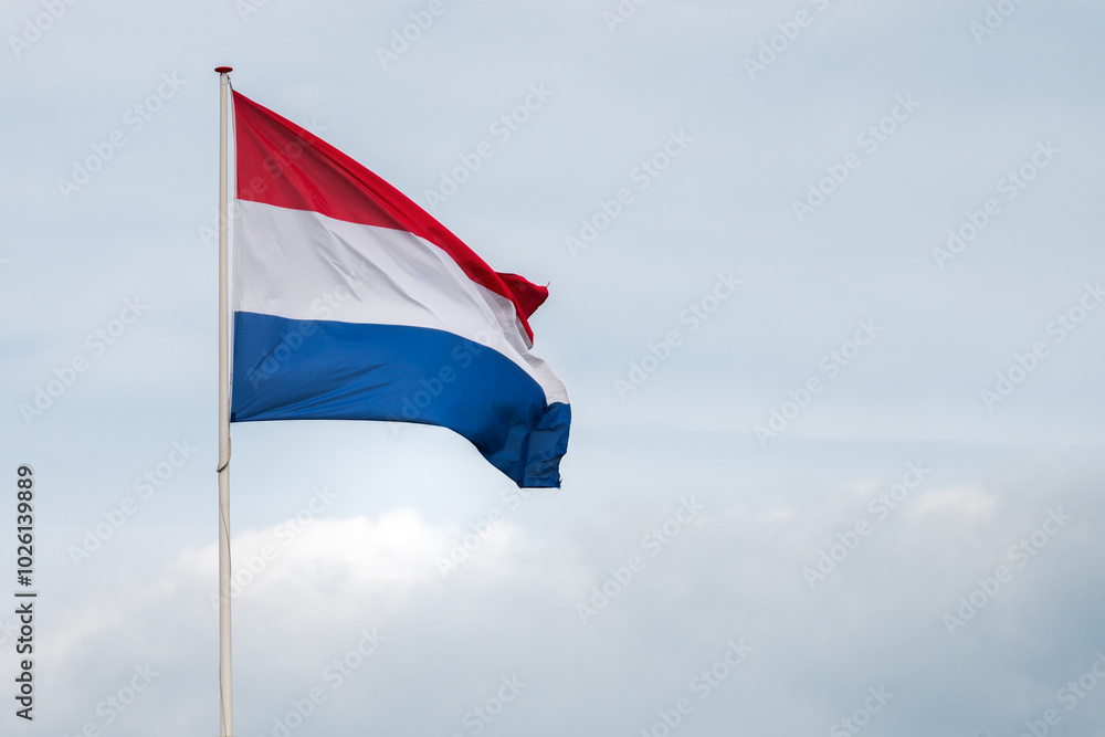 The flag of the Netherlands fluttering in the wind. Red, White and Blue. National pride and unity. The spirit of patriotism in Holland. Sky, water or buildings in the background. The flag of the Netherlands fluttering in the wind. Red, White and Blue. National pride and unity. The spirit of patriotism in Holland. Sky, water or buildings in the background.