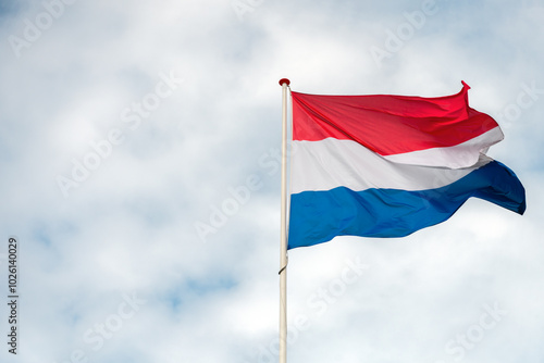 The flag of the Netherlands fluttering in the wind. Red, White and Blue. National pride and unity. The spirit of patriotism in Holland. Sky, water or buildings in the background.