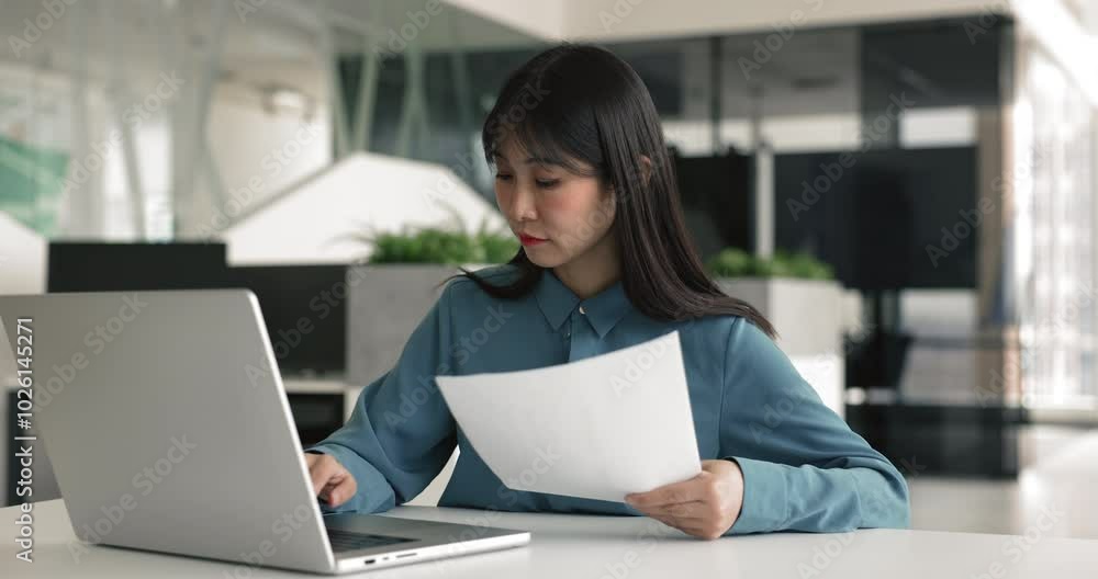 Asian woman working in office, using laptop, review papers, makes financial report, analyze company performance and plan budgets, engaged in project plans preparation, track progress, make adjustments Asian woman working in office, using laptop, review papers, makes financial report, analyze company performance and plan budgets, engaged in project plans preparation, track progress, make adjustments