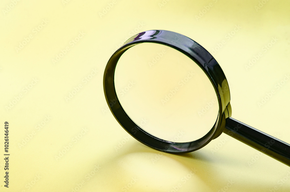 Side view of magnifying glass on yellow cover background with customizable space for text or ideas Side view of magnifying glass on yellow cover background with customizable space for text or ideas