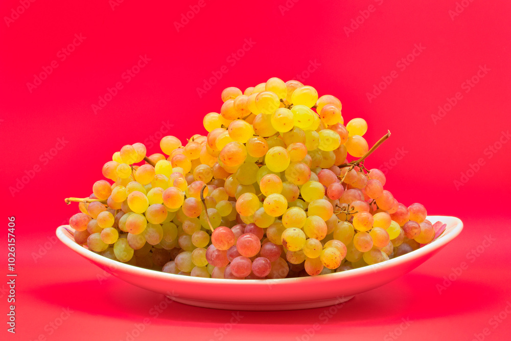 Plate with kishmish (sultana) grapes on a red background