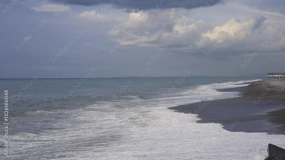 A serene beach scene with gentle waves rolling onto a pebble shoreline under a cloudy sky. The horizon stretches endlessly, creating a peaceful and calming coastal atmosphere. Perfect for nature. A serene beach scene with gentle waves rolling onto a pebble shoreline under a cloudy sky. The horizon stretches endlessly, creating a peaceful and calming coastal atmosphere. Perfect for nature.
