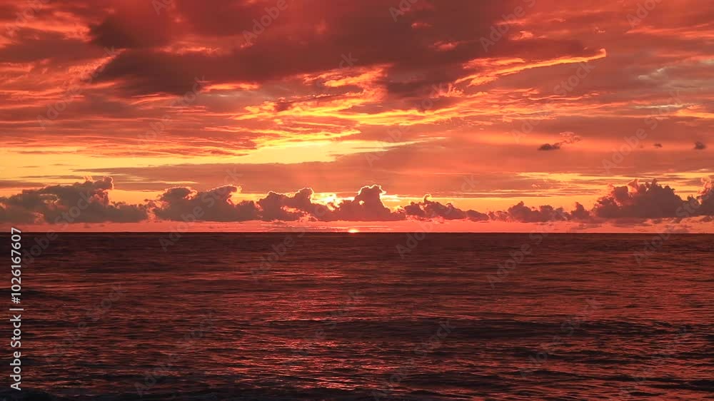 A stunning ocean sunset with vivid orange and red hues filling the sky.Dark clouds create dramatic contrast against the glowing horizon, while the calm sea reflects the fiery colors of the setting sun A stunning ocean sunset with vivid orange and red hues filling the sky.Dark clouds create dramatic contrast against the glowing horizon, while the calm sea reflects the fiery colors of the setting sun