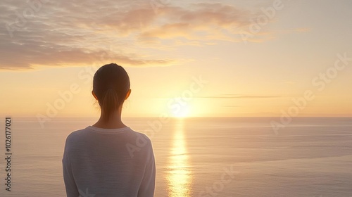 Woman watching a sunrise over the ocean, peaceful and awefilled, warm tones