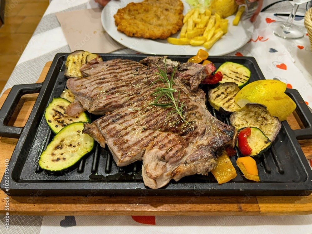 grilled ribs with vegetables and lemon on the table on a cast iron tray