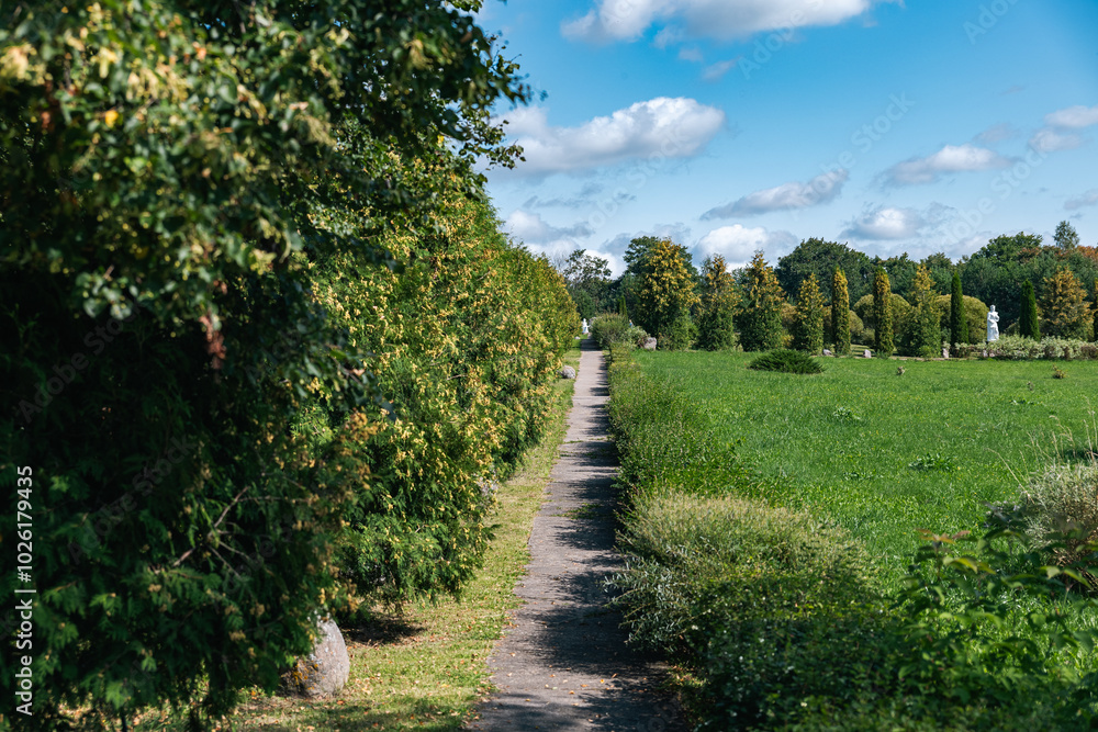 Path winding through a beautifully landscaped park. The path is framed by lush greenery on either side, creating a sense of privacy and tranquility. Path winding through a beautifully landscaped park. The path is framed by lush greenery on either side, creating a sense of privacy and tranquility.