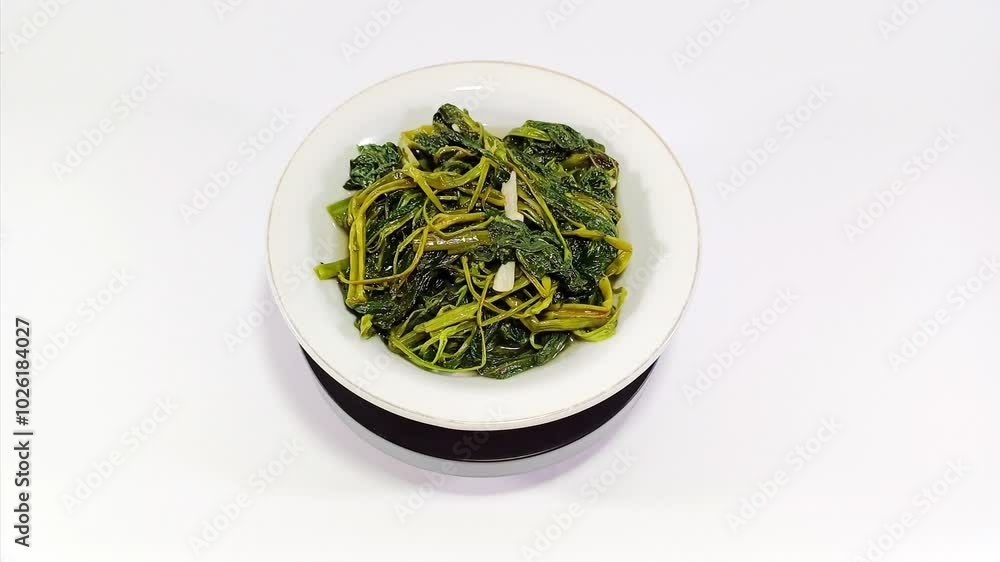 Stir-fried green water spinach (morning glory) served in a small white round bowl against a clean white background, showcasing a fresh and vibrant vegetable dish perfect for a healthy meal Stir-fried green water spinach (morning glory) served in a small white round bowl against a clean white background, showcasing a fresh and vibrant vegetable dish perfect for a healthy meal