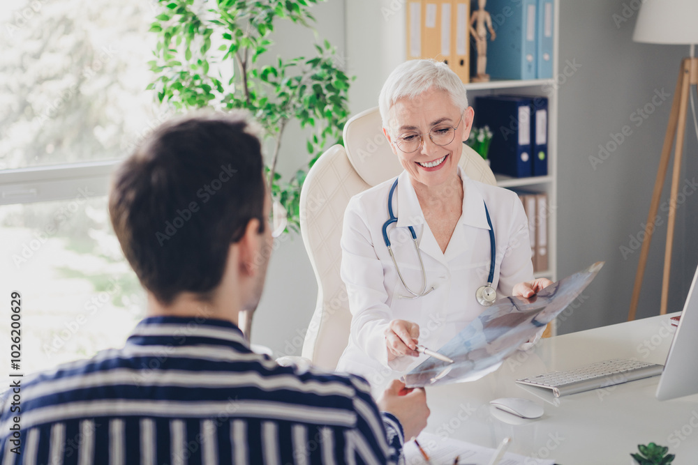 Fototapeta premium Photo of aged woman qualified doctor show x-ray patient man wear white coat workplace office indoors