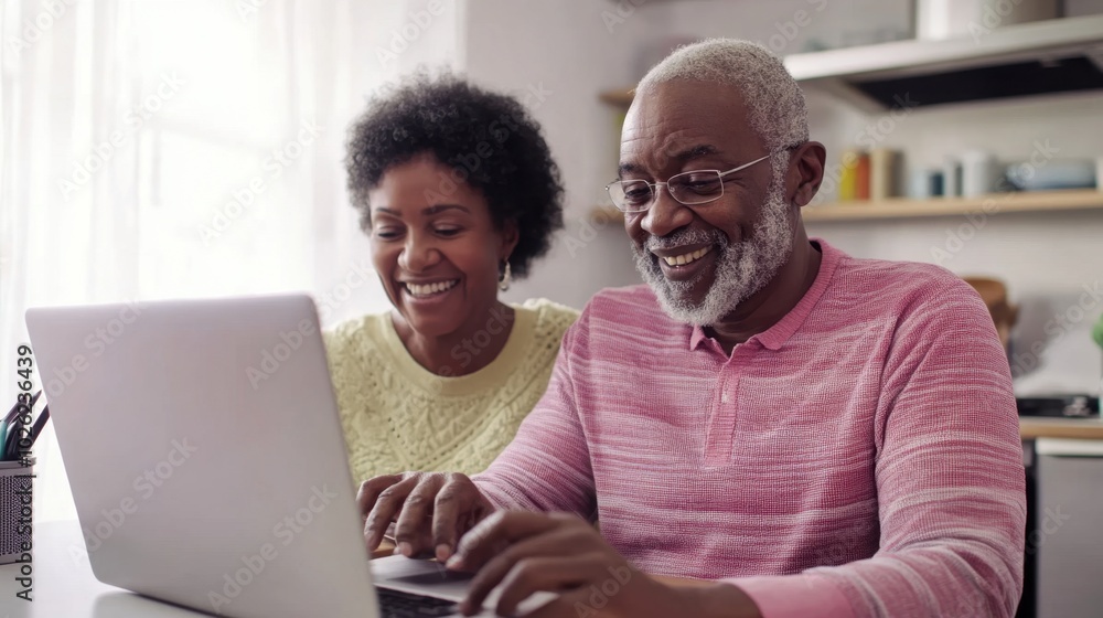 Fototapeta premium Elderly couple using laptop at kitchen table, bright lighting, clean background, copy space