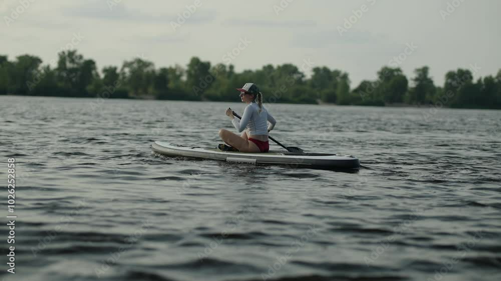 Paddler exploring tranquil river on stand-up paddle board Paddler exploring tranquil river on stand-up paddle board