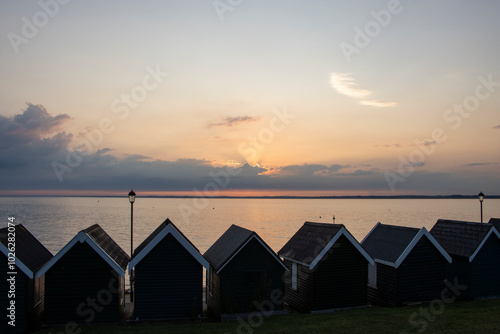 Beach huts at Gurnard, Cowes, Isle of Wight at sunset.  Looking over the western Solent