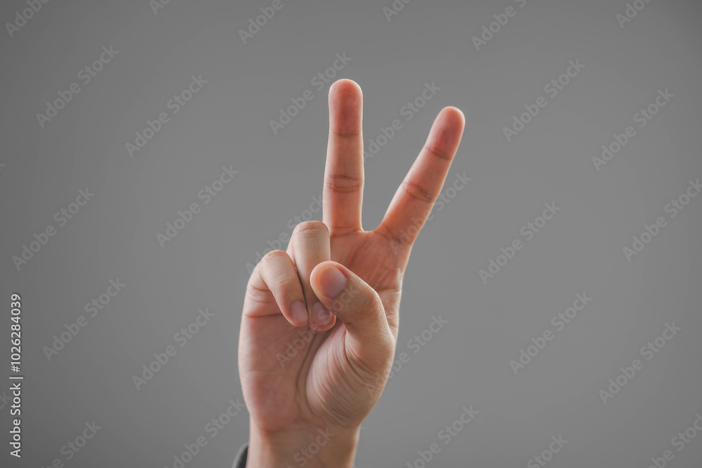 A hand showing a peace sign, symbolizing harmony and positivity against a neutral background. A hand showing a peace sign, symbolizing harmony and positivity against a neutral background.