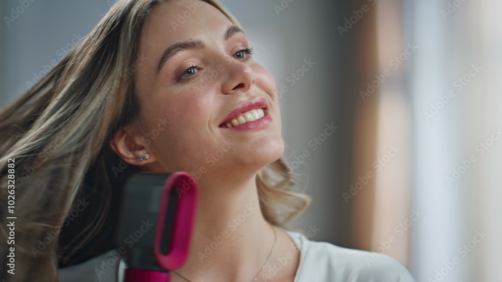 Happy housewife holding dryer touching hair in bathroom closeup. Beauty woman