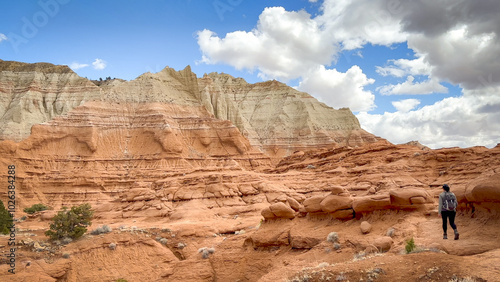 Female hiker walking through a stunning landscape of unique red rock formations on a beautiful day. The blue sky contrasts against the orange colors of Kodachrome Basin State Park in Utah, USA.