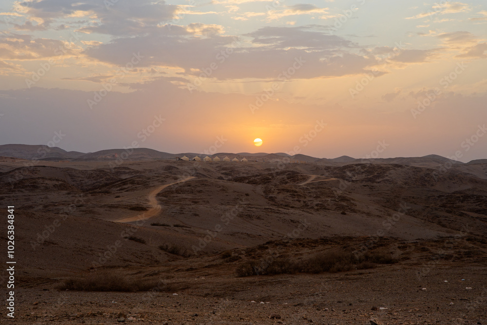coucher de soleil dans le désert marocain avec au loin un camp de tentes berbère coucher de soleil dans le désert marocain avec au loin un camp de tentes berbère