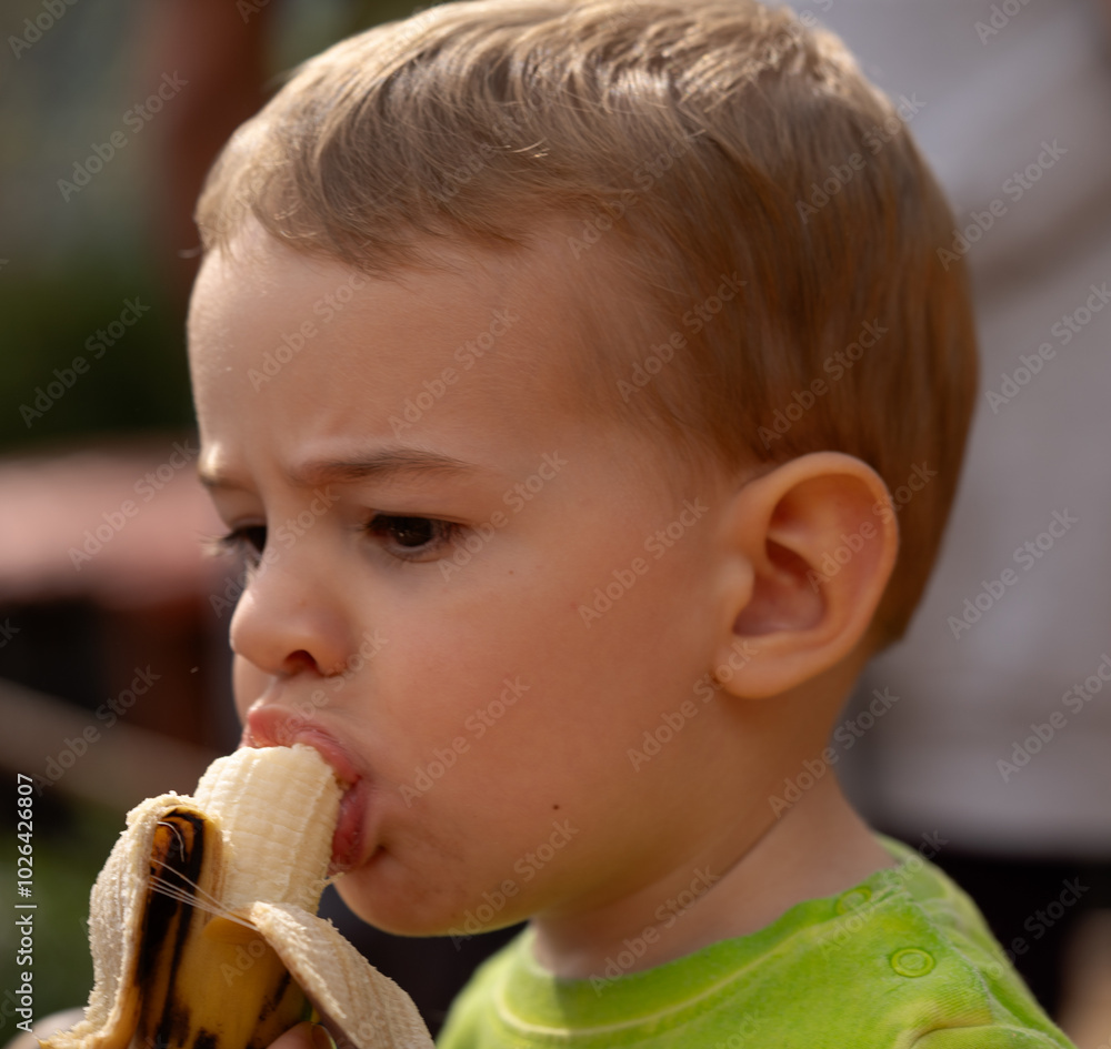 child snacking on a banana in the open air child snacking on a banana in the open air