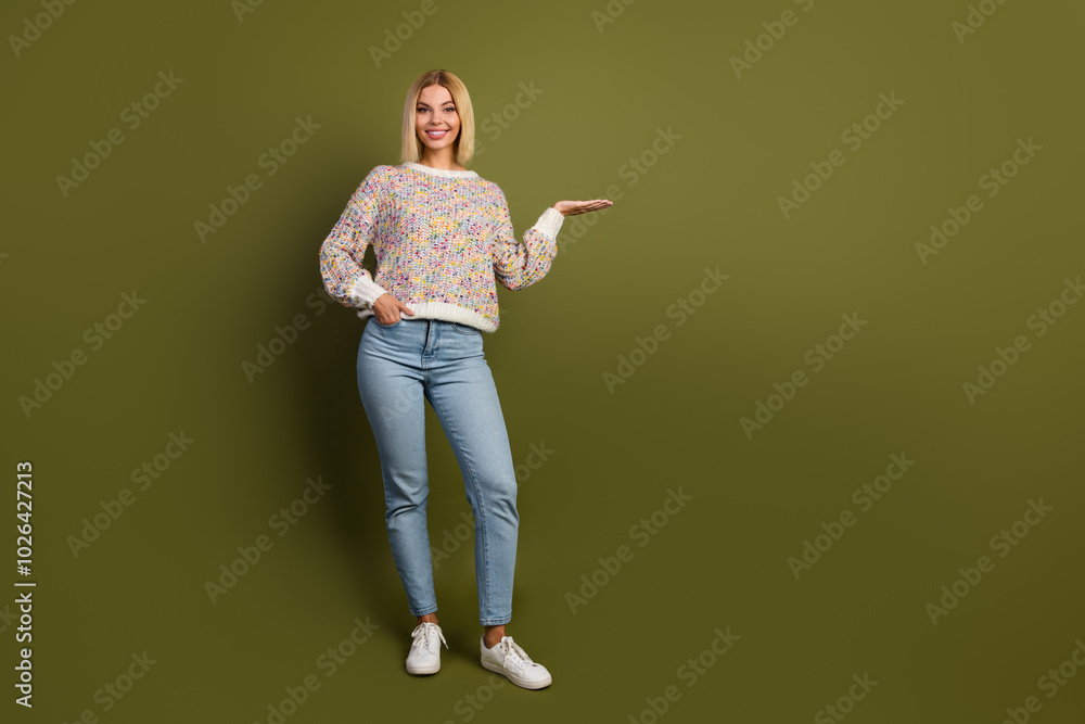 Young woman in colorful knitwear sweater gesturing on green background for advertisement concept Young woman in colorful knitwear sweater gesturing on green background for advertisement concept