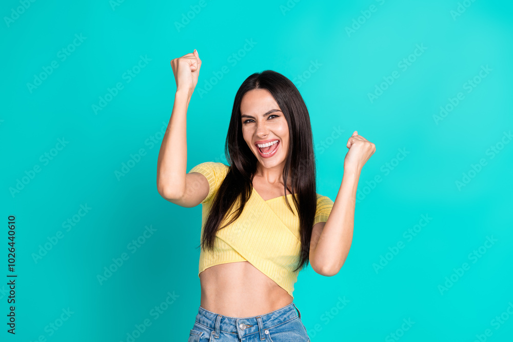 Portrait of pretty young woman raise fists wear top isolated on turquoise color background Portrait of pretty young woman raise fists wear top isolated on turquoise color background