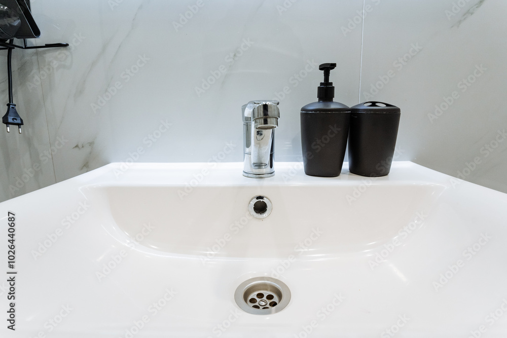 The stylish bathroom features a contemporary sink with a sophisticated faucet and two soap dispensers, ensuring hygiene and a delightful handwashing experience for all users The stylish bathroom features a contemporary sink with a sophisticated faucet and two soap dispensers, ensuring hygiene and a delightful handwashing experience for all users