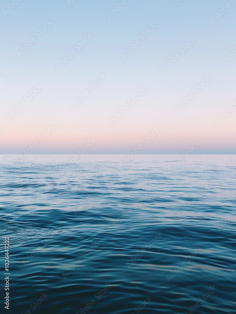 Obraz premium A peaceful ocean scene with gentle waves rippling under a soft sunset sky, creating a calm and tranquil atmosphere.