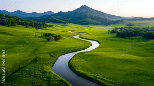 A dirt path winds through vibrant green fields, leading towards distant mountains under an overcast sky. The scene captures the beauty of nature in a serene landscape during early morning