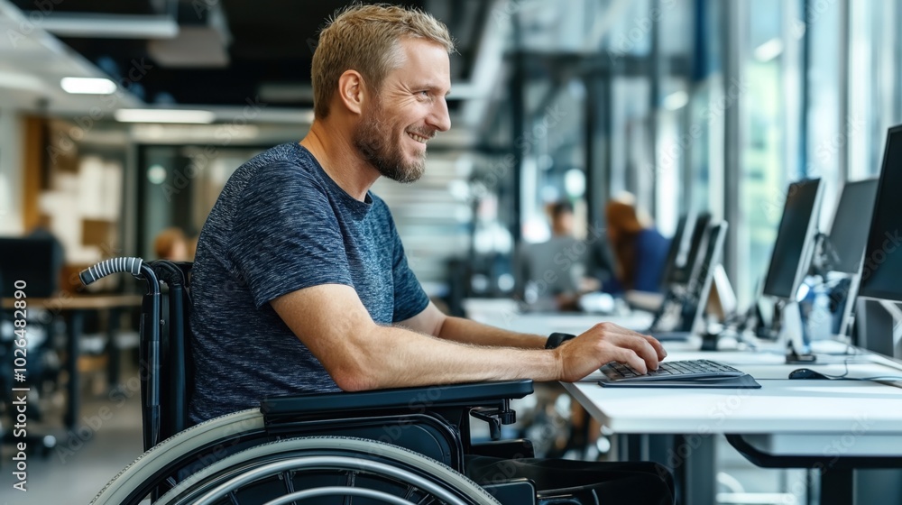 Man in a wheelchair working at a computer in a modern office environment, smiling and engaged. Man in a wheelchair working at a computer in a modern office environment, smiling and engaged.