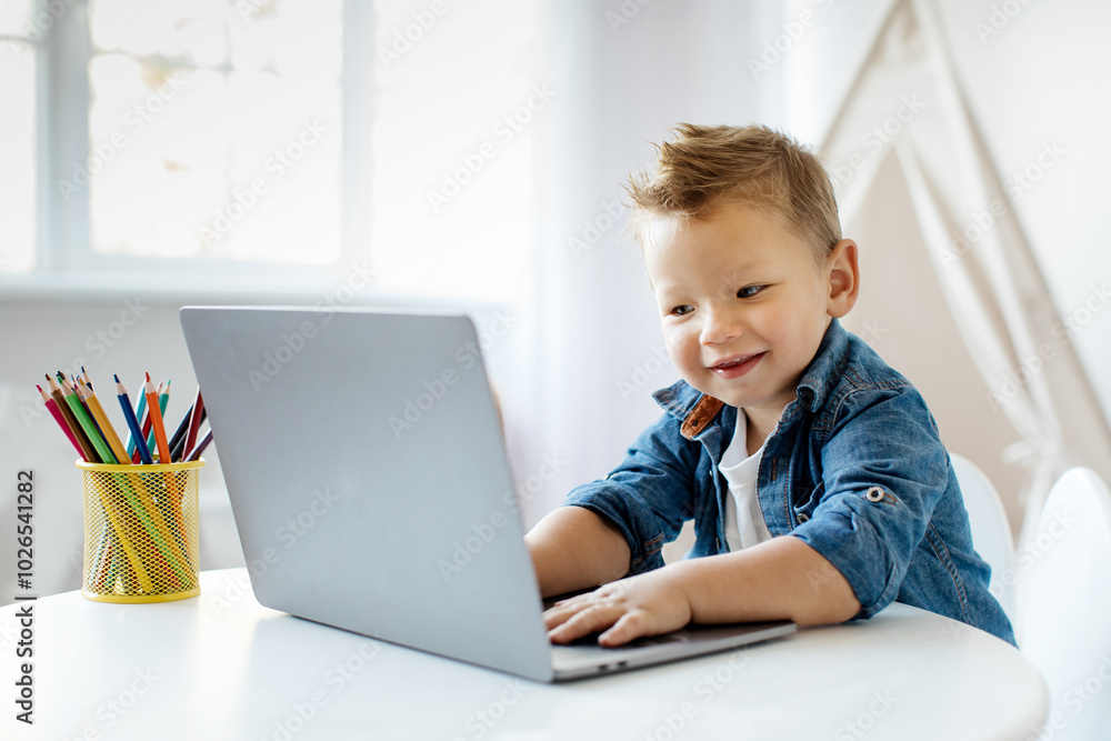 Online Education. Cute Smiling Little child sits at a table, using a laptop with enthusiasm. The bright workspace is adorned with colorful art supplies, creating a creative atmosphere. Online Education. Cute Smiling Little child sits at a table, using a laptop with enthusiasm. The bright workspace is adorned with colorful art supplies, creating a creative atmosphere.