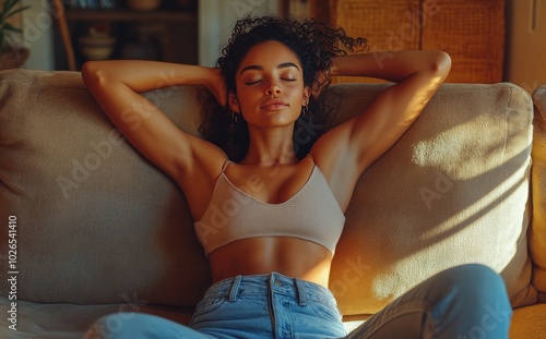 Relaxing in natural light, a young woman enjoys a peaceful moment on a cozy sofa