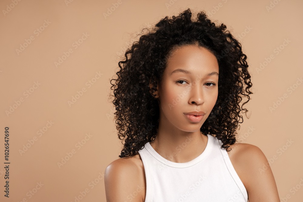 Beautiful African American woman looking at camera against beige background in studio Beautiful African American woman looking at camera against beige background in studio