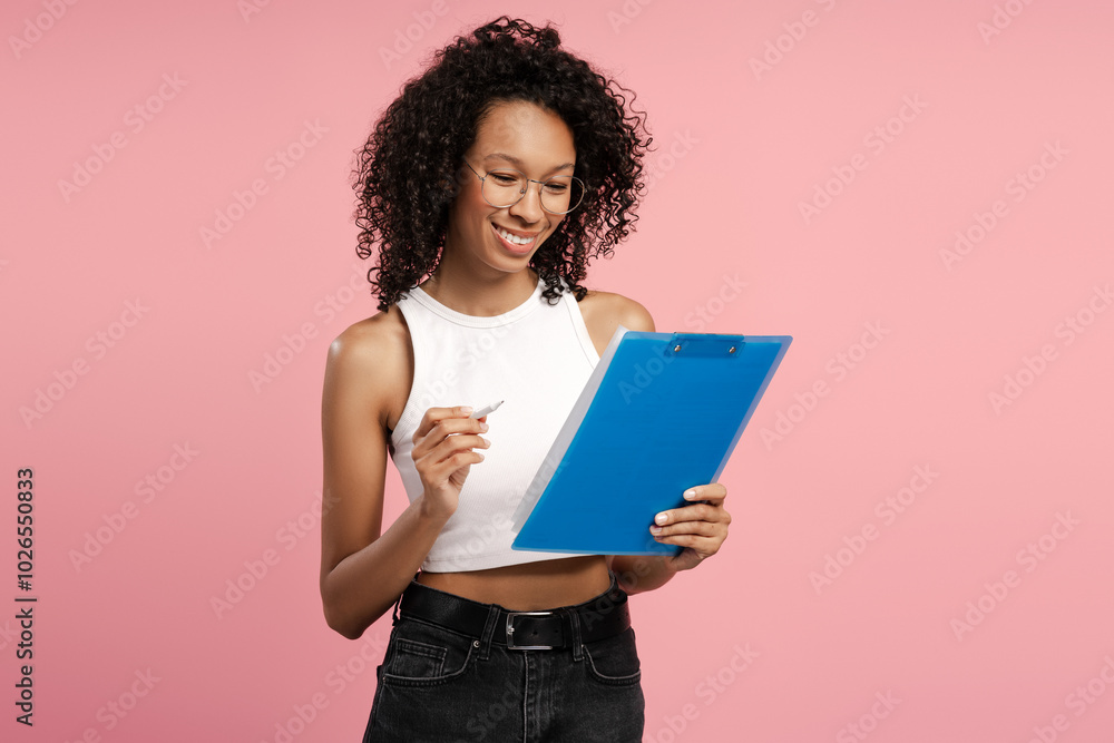 Portrait of businesswoman holding clipboard and pen isolated on pink background Portrait of businesswoman holding clipboard and pen isolated on pink background