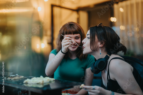 Two young women share happy moments while enjoying a meal together. A casual dining setting accentuates their friendship and connection.