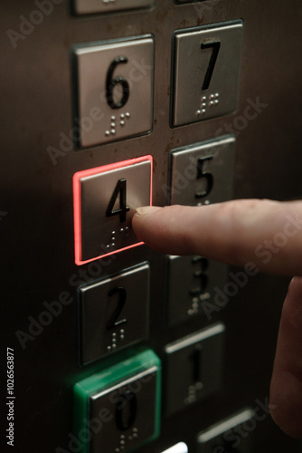 buttons in a new elevator with braille, a man presses button four
