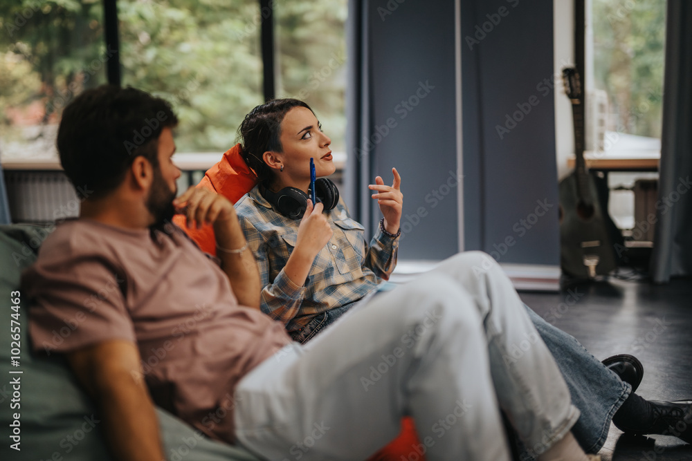 A young man and woman engage in a thoughtful discussion while relaxing in a modern room. The atmosphere is casual and intellectual, capturing a moment of connection and shared ideas. A young man and woman engage in a thoughtful discussion while relaxing in a modern room. The atmosphere is casual and intellectual, capturing a moment of connection and shared ideas.