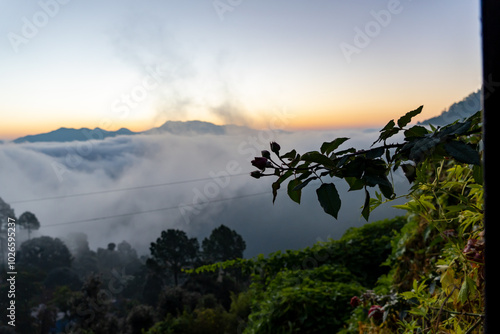 Before sunrise view, painted sky with soft orange light in the horizon. Dense clouds covers the valley and mountains in background above the clouds. Magical morning scene in mountain village in India. photo